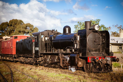 Train on railroad track amidst field against sky