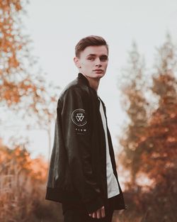 Portrait of young man standing against tree