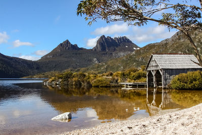 Scenic view of dove lake with boat shed and mountains against sky
