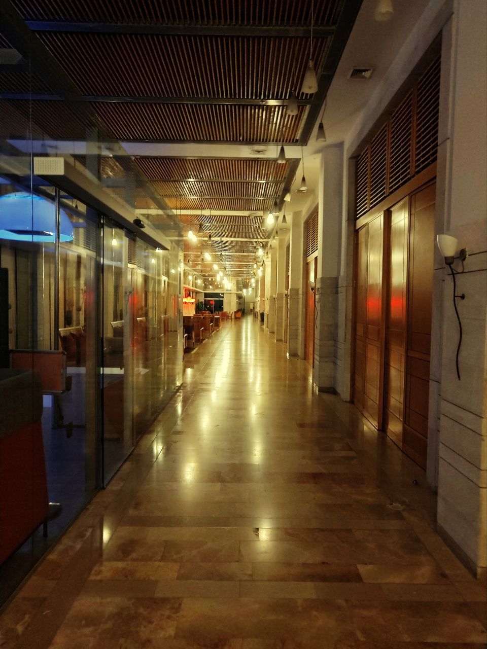 EMPTY CORRIDOR ALONG ILLUMINATED BUILDING