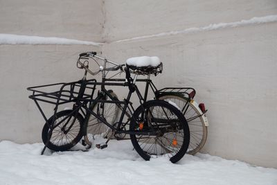 Bicycle parked on snow covered wall