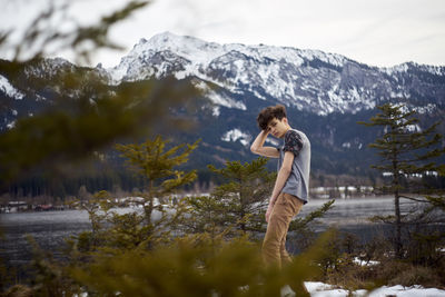 Portrait of young man standing against snowcapped mountain