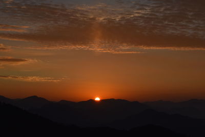 Scenic view of silhouette mountains against romantic sky at sunset