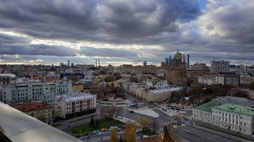 High angle view of city buildings against cloudy sky