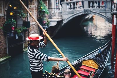 Man with umbrella on bridge over canal