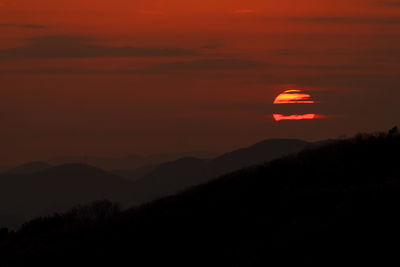 Scenic view of silhouette mountains against orange sky