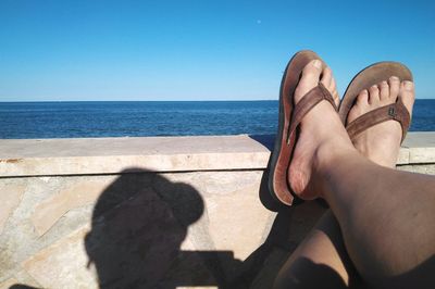 Low section of woman on beach against clear sky