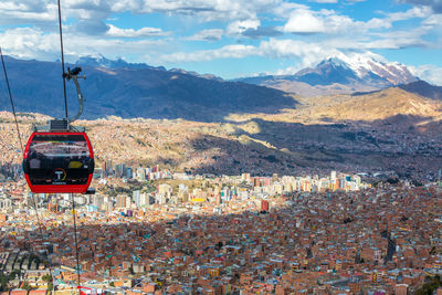 Cable car over cityscape against sky