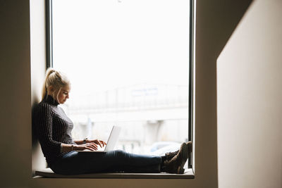 Smiling woman sitting on windowsill