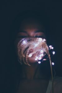 Close-up portrait of young woman against black background