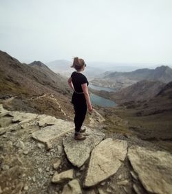 Woman standing on rock against sky