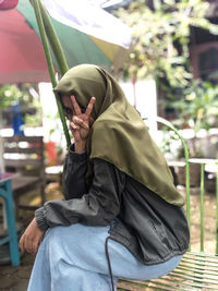 Portrait of woman gesturing while sitting outdoors