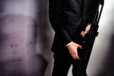 Midsection of businessman standing against wall