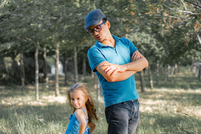 Father and daughter standing back to back while standing on land