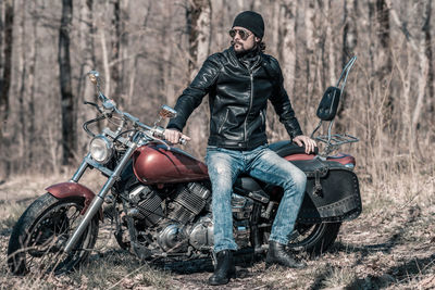 Mid adult man sitting on motorcycle in forest