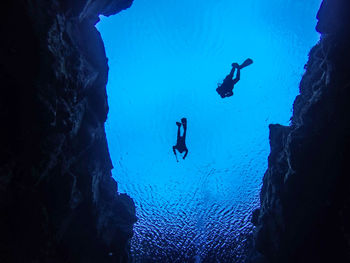 Low angle view of silhouette people swimming in sea