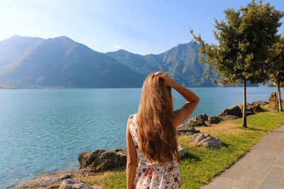 Rear view of woman looking at lake by mountains