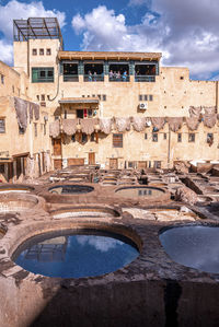 Dyed water fill in tanks in tannery against old residential building