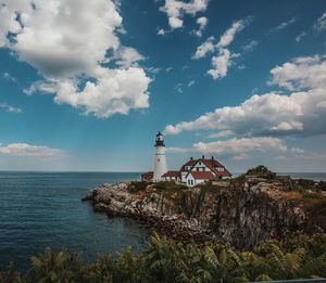 Lighthouse by sea against sky