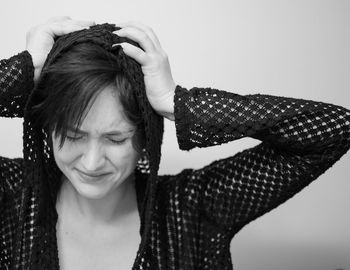 Close-up of young woman holding head during headache against wall