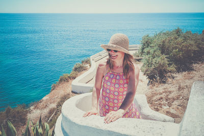 Portrait of young woman standing by sea