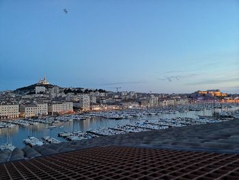 Sailboats in sea by town against clear blue sky
