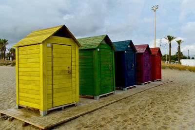 Multi colored huts on beach by buildings against sky