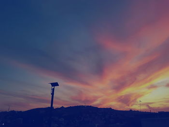 Road sign against sky at sunset