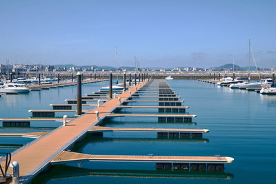 Boats moored at harbor against blue sky