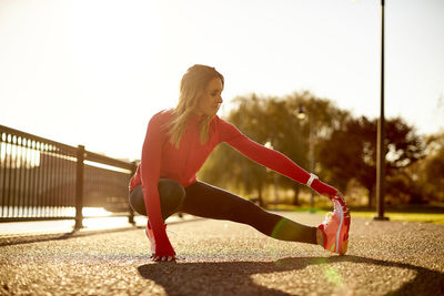 A female runner stretching in a city park.