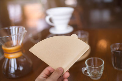 Cropped hand of woman holding drink on table