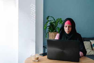 Young woman using mobile phone while sitting on table