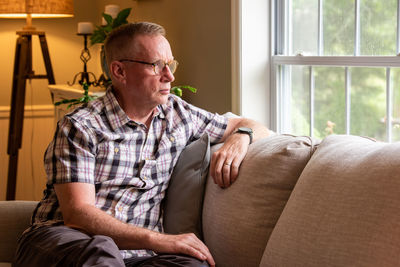 Midsection of man sitting on sofa at home