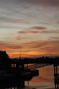 Silhouette boats moored in lake against sky during sunset