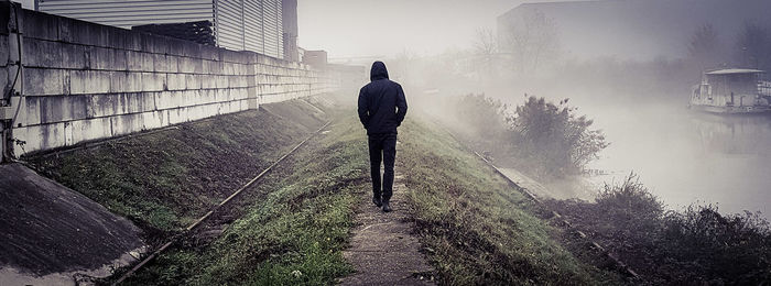 Rear view of man walking on road against sky