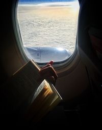 Cropped image of hand on car window against sky