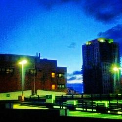 Illuminated buildings against blue sky at night