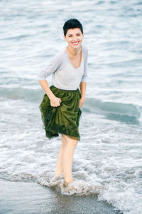 Portrait of smiling woman standing on shore at beach