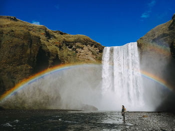 Scenic view of waterfall with rainbow in sky