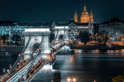 Illuminated bridge over river at night