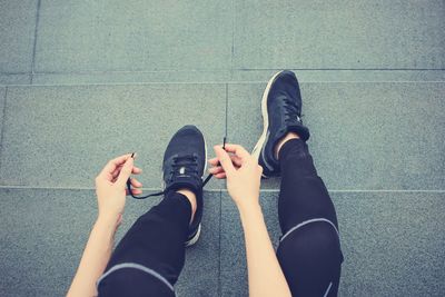 Low section of woman tying shoelace while sitting on steps