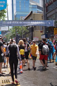 Rear view of people walking on road along buildings