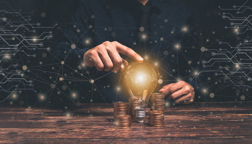 Digital composite image of hand holding illuminated light on table