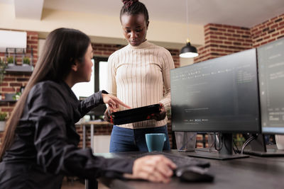 Side view of woman using digital tablet while sitting on table