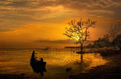 Silhouette people on boat against sky during sunset