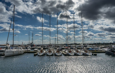 Sailboats moored in harbor against sky