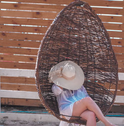 Side view of boy holding hat sitting outdoors