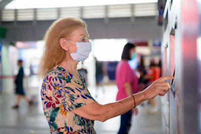 Midsection of woman using mobile phone while standing by train