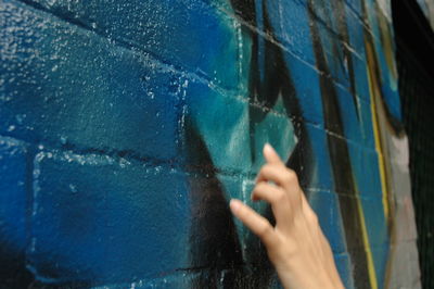 Close-up of hand holding blue wall