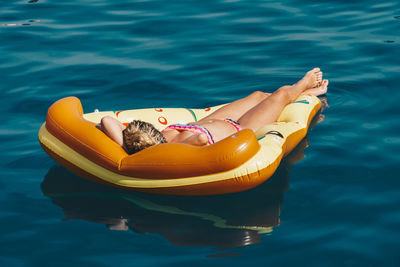 High angle view of woman in bikini relaxing on inflatable raft in pool